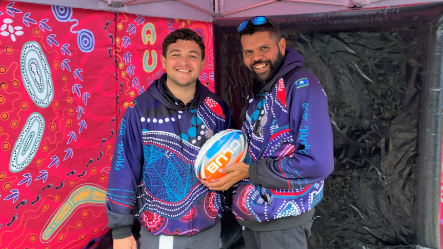 Ash Taylor and Alfred Orcher holding a football at NAIDOC Week