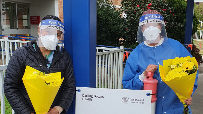 Warwick testing staff in face shields holding bunches of flowers at COVID-19 clinic