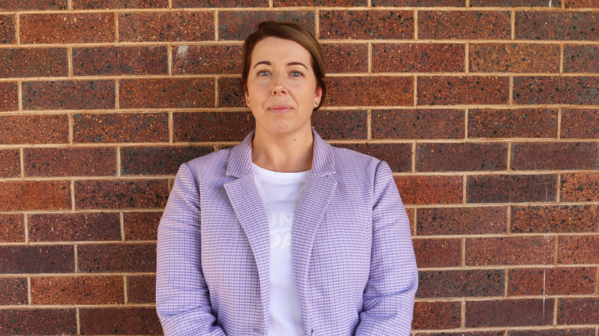 Photo of a staff member standing against a brick wall