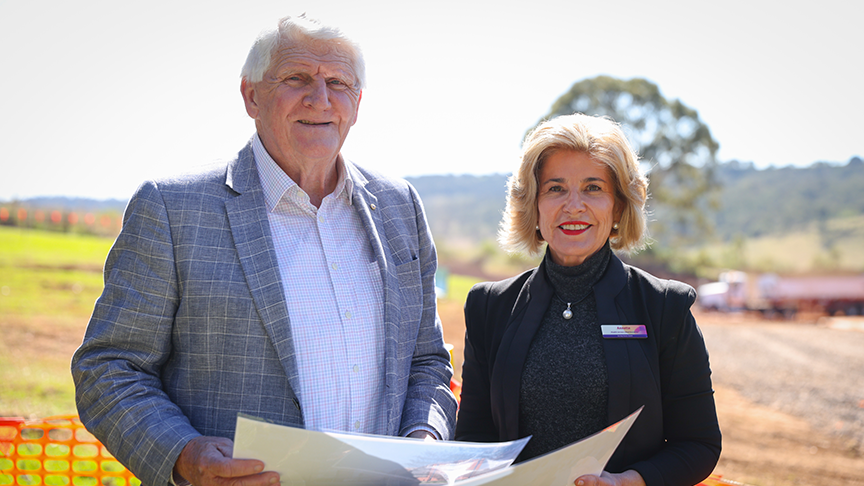 Board chair, Mike Horan with Chief Executive Annette Scott standing outside holding a folder containing the annual report