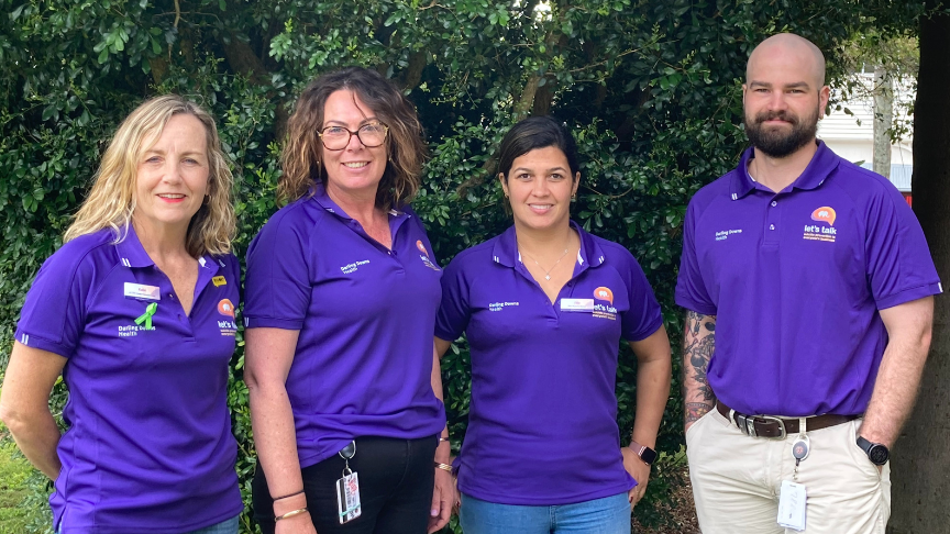 Katie Hangan, Robyn Eastwell, Ellie de Paula, Liam Brennan standing outside wearing their purple mental health promotion polo shirts 