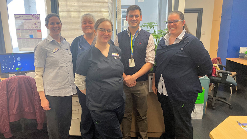 Five staff members standing together smiling