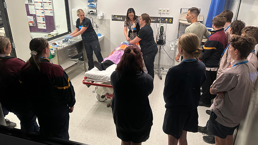 High school students standing around a hospital bed watching an emergency department simulation