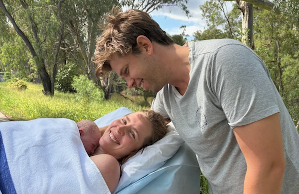 Woman holding newborn with male looking at them